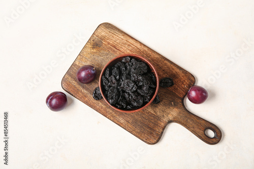 Bowl with tasty prunes and ripe plums on white grunge table