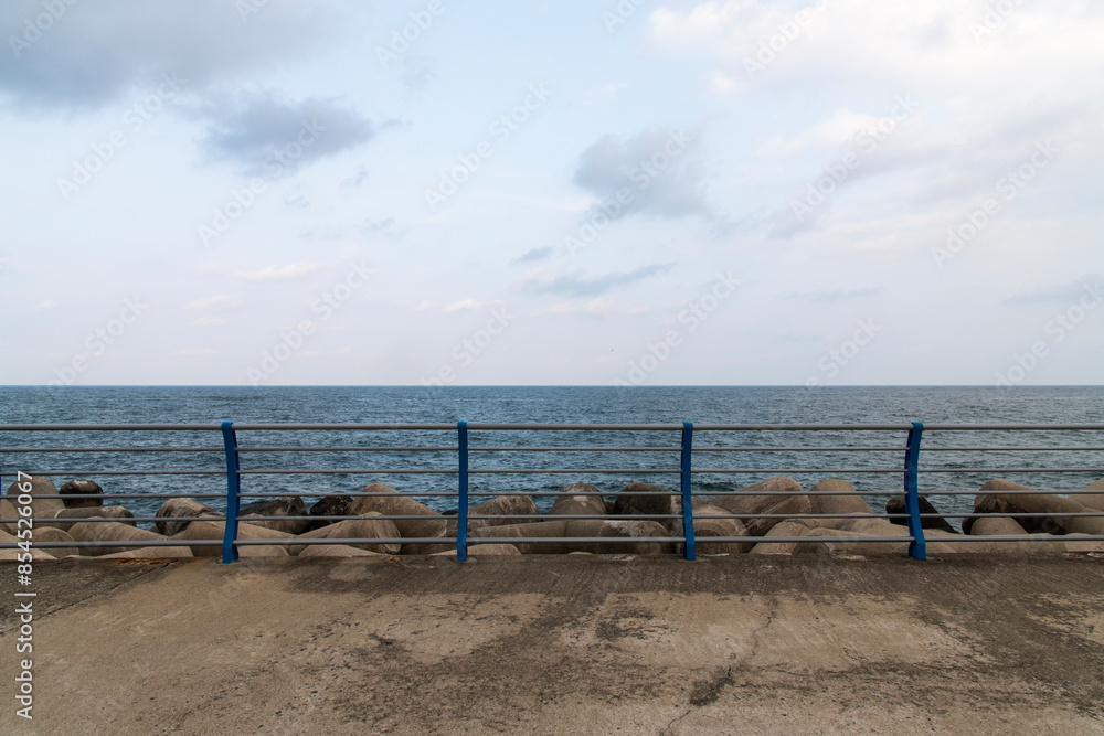 View of the fence on the seawall and cloudy sea