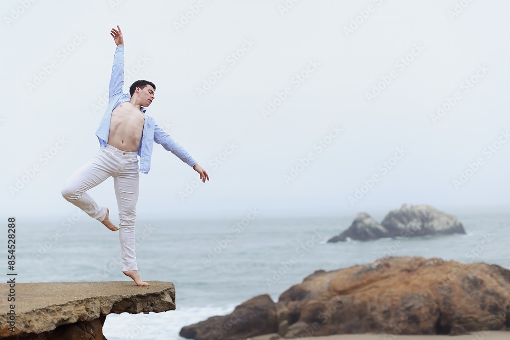 Male ballet dancer perfromance artist on the beach balancing on a concrete structure Male ballet dancer perfromance artist on the beach balancing on a concrete structure