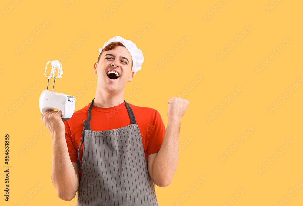 Male confectioner in apron with mixer and whipped meringue on yellow background Male confectioner in apron with mixer and whipped meringue on yellow background