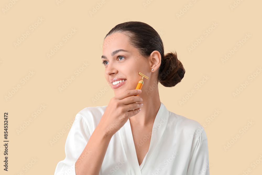 Beautiful young woman massaging her face with tool on beige background, closeup Beautiful young woman massaging her face with tool on beige background, closeup