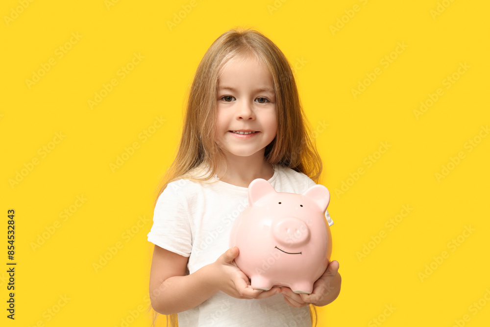 Cute little girl with piggy bank on yellow background Cute little girl with piggy bank on yellow background
