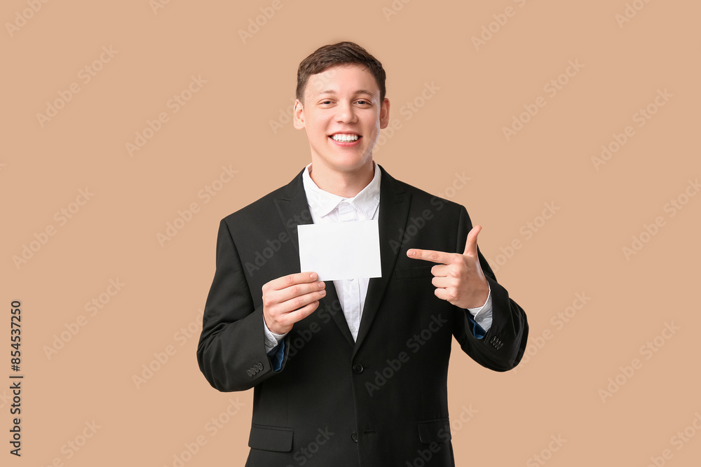 Young man pointing at blank ballot on beige background Young man pointing at blank ballot on beige background