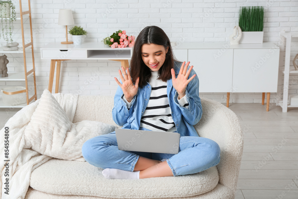 Young woman with laptop having online date on sofa at home Young woman with laptop having online date on sofa at home