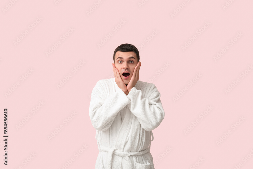 Portrait of shocked young man in bathrobe on pink background Portrait of shocked young man in bathrobe on pink background