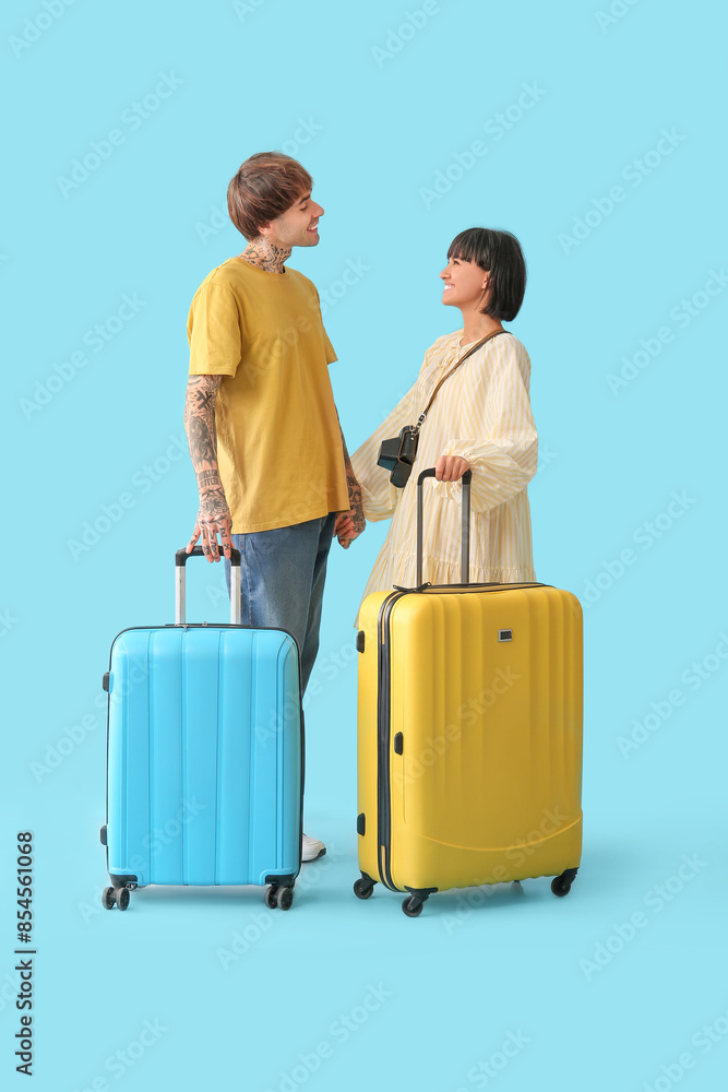 Couple of young tourists with suitcases on blue background Couple of young tourists with suitcases on blue background