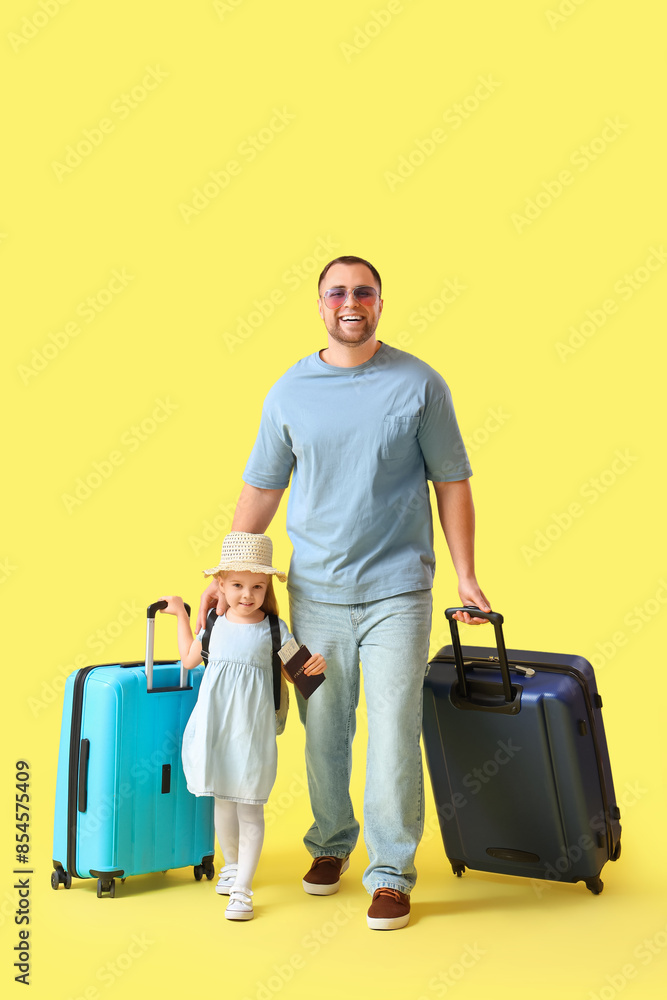 Young happy father in sunglasses with his little daughter and suitcases on yellow background Young happy father in sunglasses with his little daughter and suitcases on yellow background