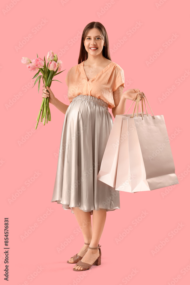 Young pregnant woman with tulips and shopping bags on pink background Young pregnant woman with tulips and shopping bags on pink background