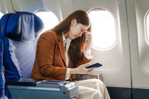 A young Asian woman is sitting in her seat as an airplane passenger, experiencing airsickness with symptoms like nausea, vomiting, dizziness, and general discomfort. photo