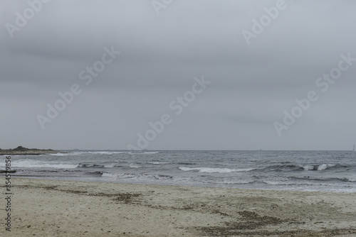 Distant Sailboat on Overcast Day at Punta Prima Beach