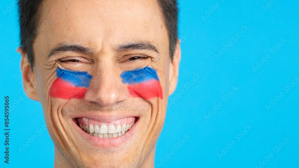 Man with a haitian flag painted on the face smiling Man with a haitian flag painted on the face smiling