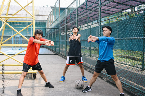 Three Young Men Stretching Their Arms Doing Warming Up On A Sport Court