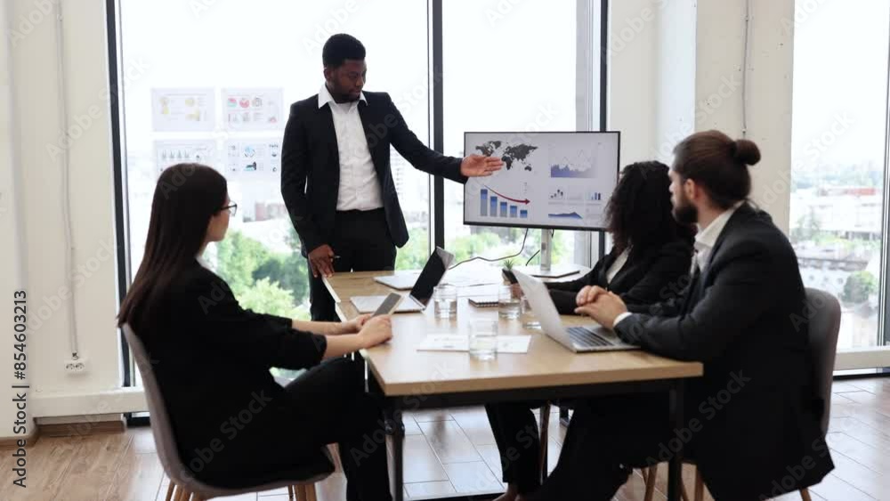 Diverse business team in formal attire having a meeting. Professional man presenting data on a screen while colleagues listen attentively. Modern office setting with city view in background Diverse business team in formal attire having a meeting. Professional man presenting data on a screen while colleagues listen attentively. Modern office setting with city view in background