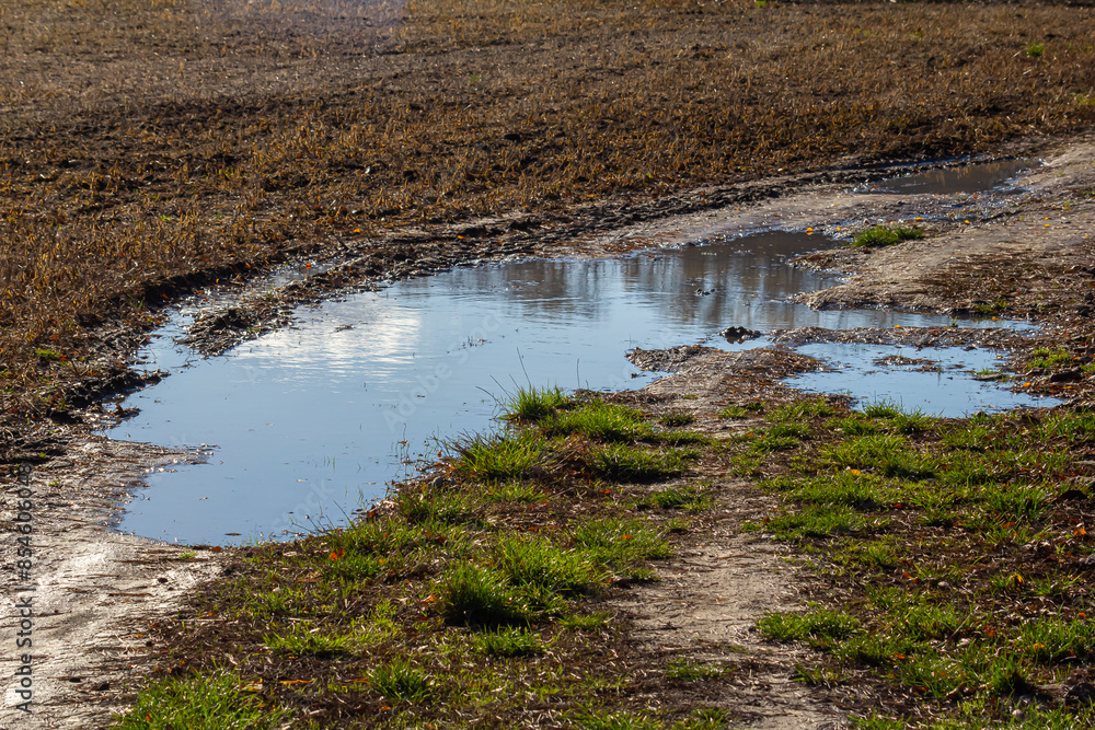 Broken country dirt road in spring mountains with lots of muddy puddles after the rain Broken country dirt road in spring mountains with lots of muddy puddles after the rain