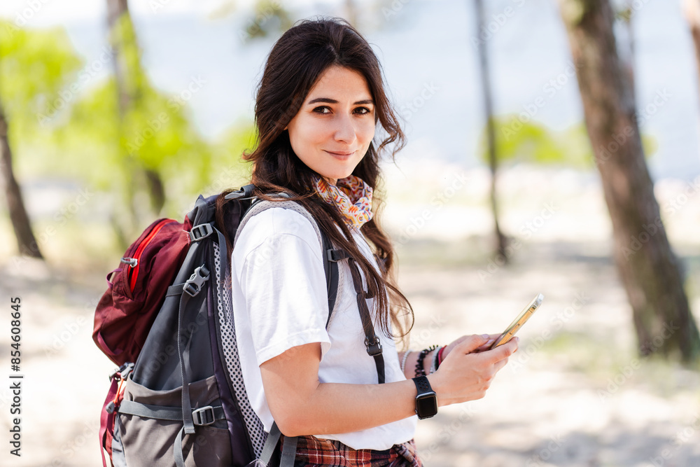 Attractive woman using smartphone and looking at camera in summer forest Attractive woman using smartphone and looking at camera in summer forest