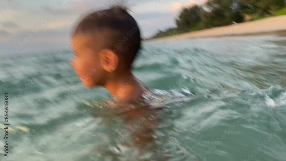 Small cute boy swimming in the sea on the sunset Small cute boy swimming in the sea on the sunset