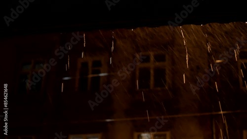 Streams of night rain flowing from the roof
