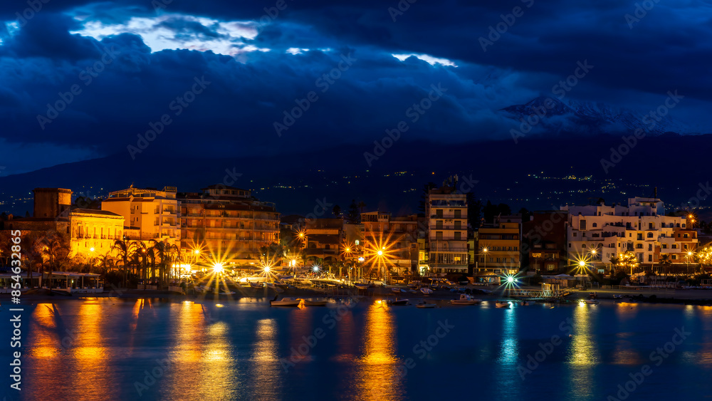 Fototapeta premium evening or night landscape of evening town coastline in golden lights and sea gulf with calm water and nice reflections with beautisul sunset sky on background