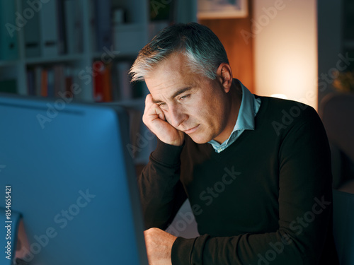 Tired businessman working late at night photo