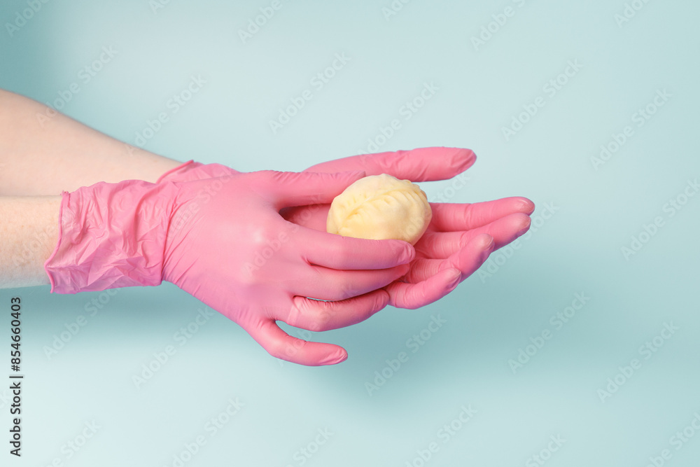 Close-up on female hands of a cook in rubber gloves holding raw mantu from dough with meat, concept of neat production of semi-finished food. Close-up on female hands of a cook in rubber gloves holding raw mantu from dough with meat, concept of neat production of semi-finished food.
