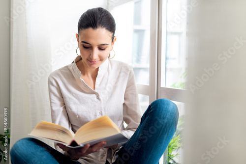 Serene woman relaxing at home and reading a book