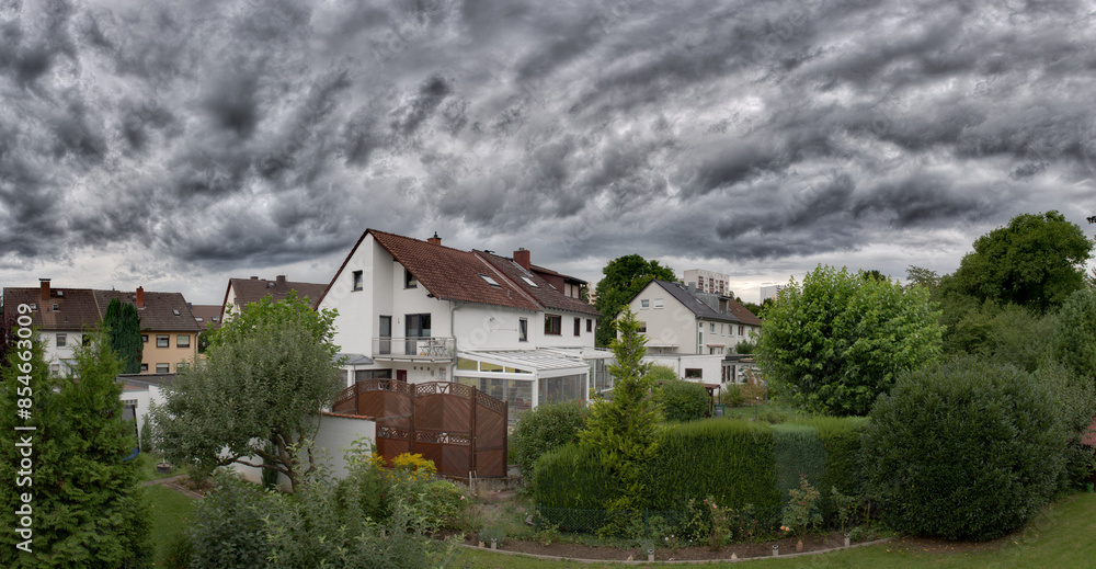 Obraz premium Eine dramatische, graue Wolkendecke über den Einfamilienhäusern einer Vorort-Wohnsiedlung mit Gärten