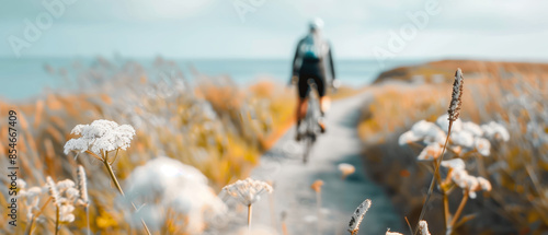 Cyclist riding on a scenic coastal path surrounded by wildflowers in bloom, capturing the beauty of summer and nature's tranquility. photo