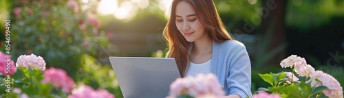 Woman working on a laptop in a vibrant garden filled with pink and white hydrangeas, warm sunlight creating a tranquil, natureinspired workspace