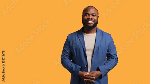 Obraz na płótnie Portrait of cheerful african american man smiling, looking pleased, isolated over yellow studio background