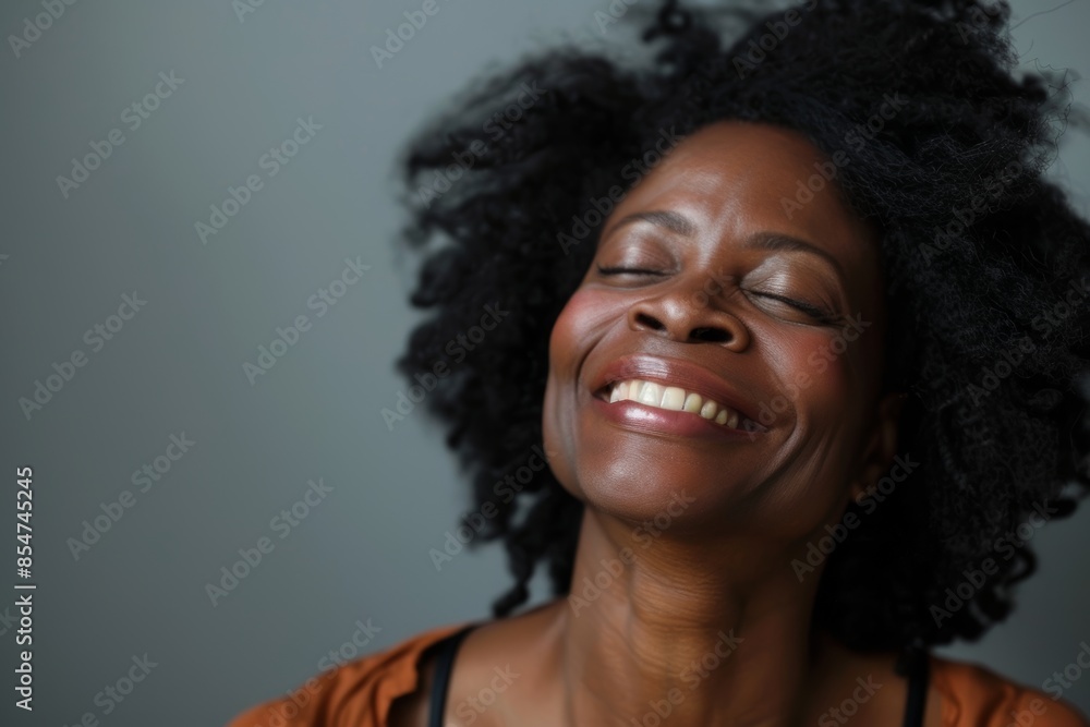 Portrait of a blissful afro-american woman in her 30s laughing isolated on soft gray background Portrait of a blissful afro-american woman in her 30s laughing isolated on soft gray background
