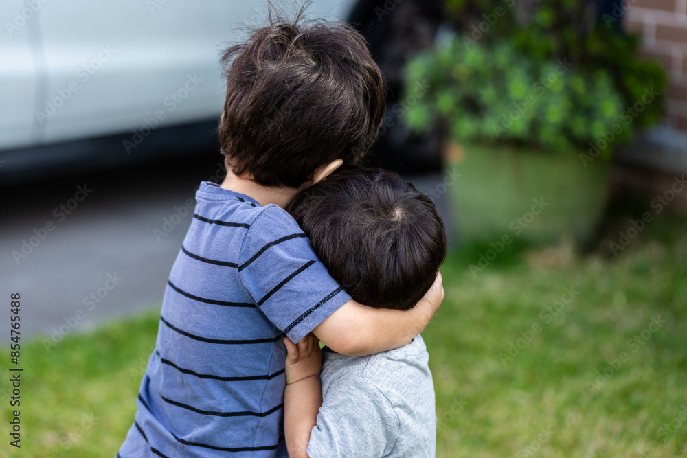 Young brothers hugging together outside home Young brothers hugging together outside home