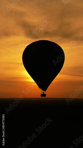Vertical video. Aerial view of silluette colorful hot air balloon flying at summer sunset photo