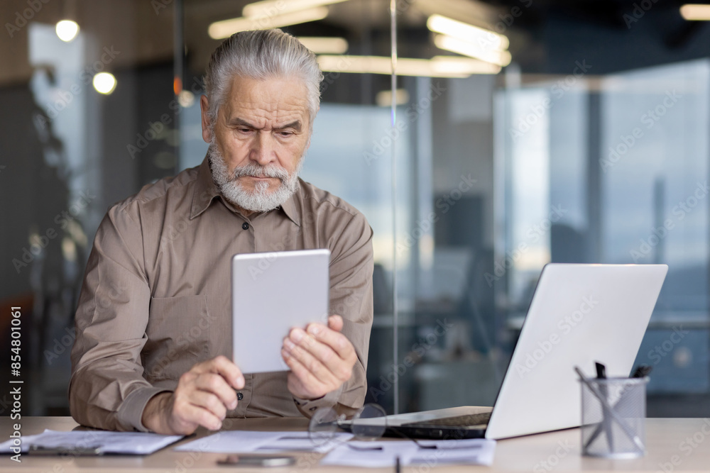 Elderly businessman in an office setting, using a digital tablet. Concept of technology, business, and senior professionals in a modern workspace. Elderly businessman in an office setting, using a digital tablet. Concept of technology, business, and senior professionals in a modern workspace.