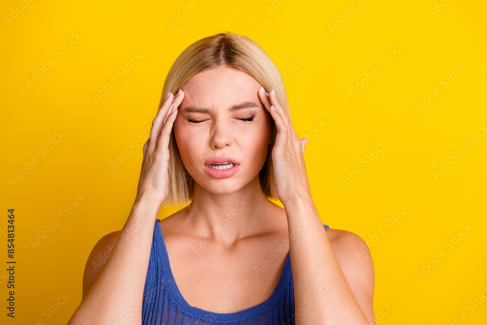 Photo portrait of young upset cute beautiful woman student suffer from headache touching temples in singlet isolated on yellow color background Photo portrait of young upset cute beautiful woman student suffer from headache touching temples in singlet isolated on yellow color background