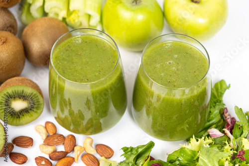 Healthy vegetable fruit nut green smoothie in glasses on a white background.