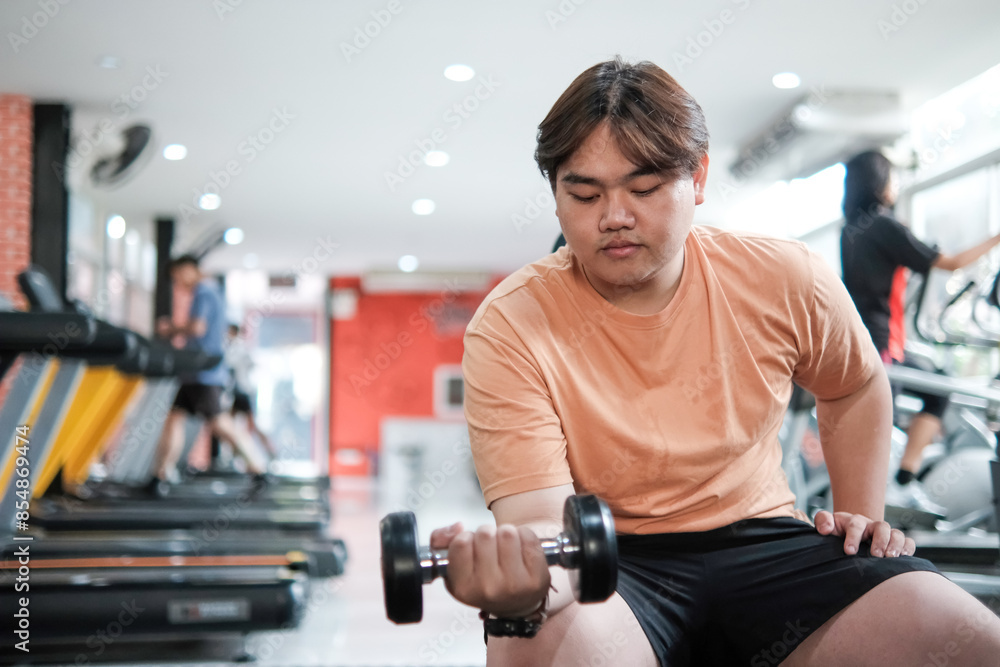 Overweight man lifting dumbbell in gym Overweight man lifting dumbbell in gym