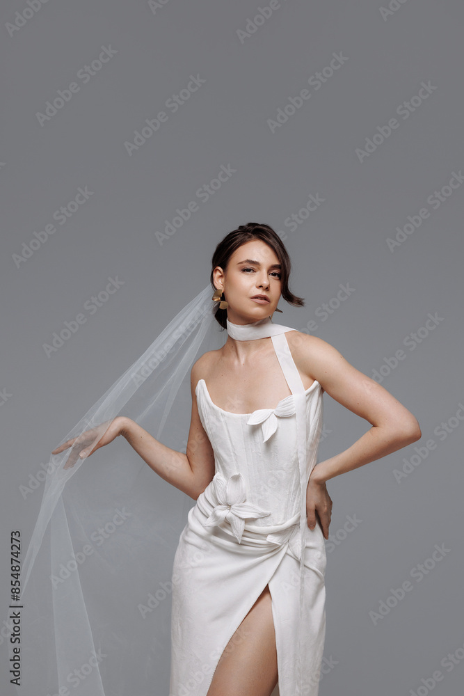Woman in a white wedding dress on a gray background. The bride chooses a dress. Concept for a collection of modern and comfortable wedding dresses.