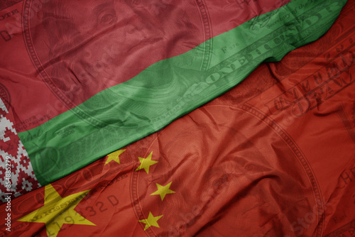 Photography waving colorful flag of belarus and national flag of china on the dollar money background