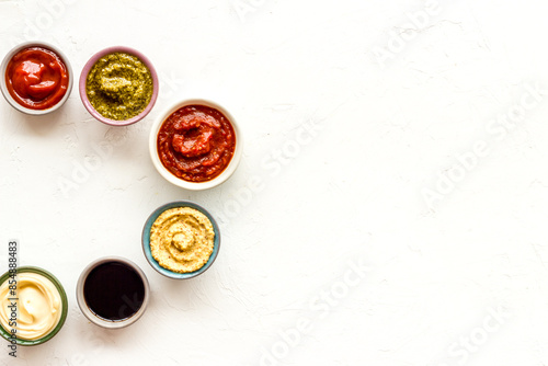 Set of sauces in bowls - pesto salsa mustard and others. Food background