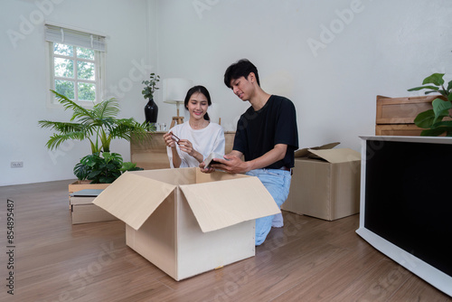 Happy Couple Unpacking Boxes in Their New Home - Moving Day, New Beginnings, and Fresh Start © Natee Meepian