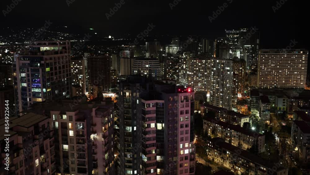 Modern high-rise buildings with light in windows in evening. Vibrant light creates lively atmosphere demonstrating energy and excitement of city living. Concept of bustling nightlife in urban Modern high-rise buildings with light in windows in evening. Vibrant light creates lively atmosphere demonstrating energy and excitement of city living. Concept of bustling nightlife in urban
