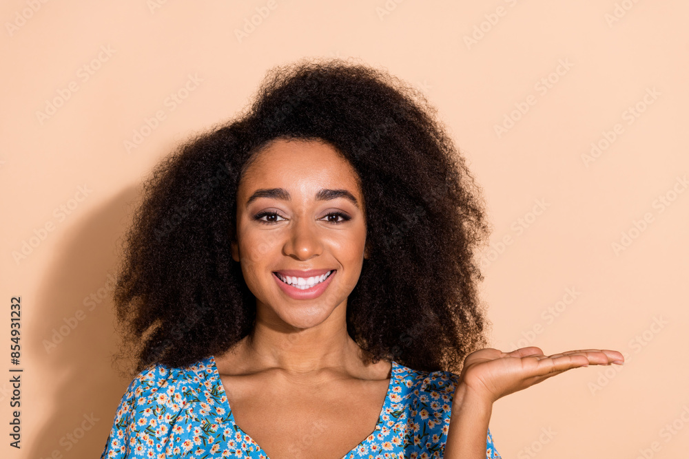 Photo of shiny attractive lady dressed blue blouse showing arm empty space isolated beige color background Photo of shiny attractive lady dressed blue blouse showing arm empty space isolated beige color background