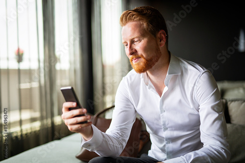 Portrait of success business man talking on mobile phone while sitting in the hotel room
