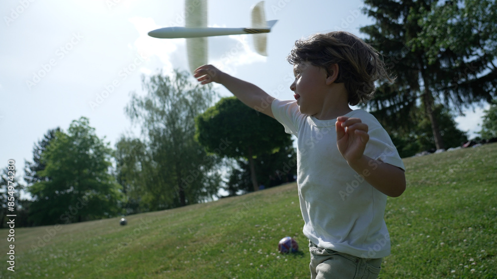 Joyful Child Playing With Toy Airplane in Sunlit Park - Summer Outdoor Fun Captured in Motion Joyful Child Playing With Toy Airplane in Sunlit Park - Summer Outdoor Fun Captured in Motion