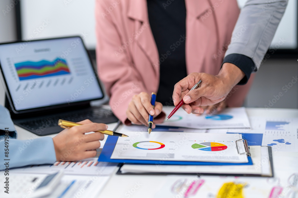 Two people are looking at a table with graphs and charts Two people are looking at a table with graphs and charts