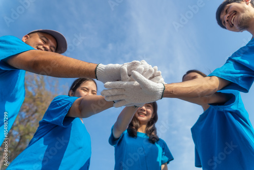 Plastic pollution and environmental problem concept. Happy asian diverse group of volunteers wearing blue t-shirt stacking hands together after cleaning plastic on the beach. © BJ Day Stock