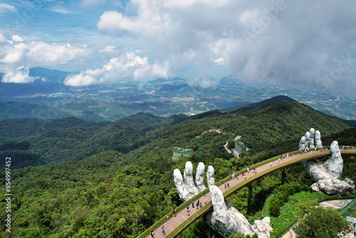 A statue holds a bridge over a river with a scenic landscape Vietnam Da Nang Ba Na Hills Asia