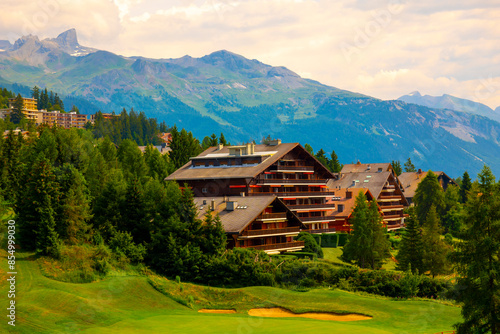 Wallpaper Mural Village with House and Hotel with Panoramic View over Mountain with Clouds and Golf Course in a Sunny Summer Day in Crans Montana, Valais, Switzerland. Torontodigital.ca