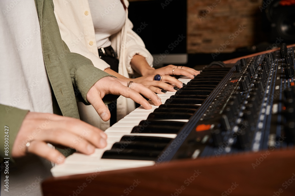 Fototapeta premium Two individuals performing music on a keyboard in a recording studio for a band rehearsal session.