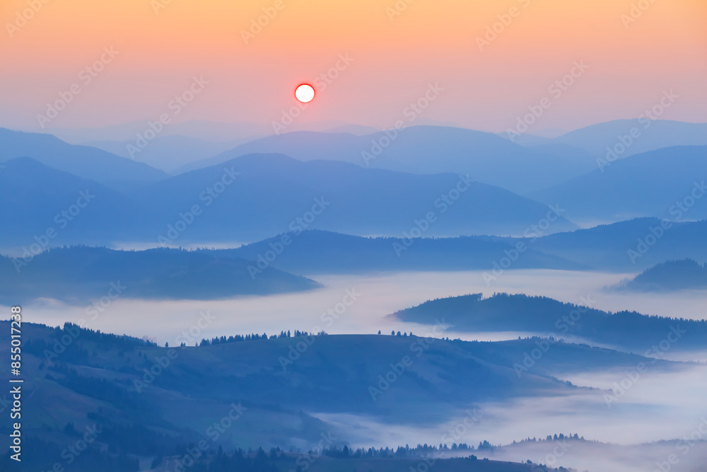 Fototapeta premium mountain chain silhouette in dense mist at the sunrise